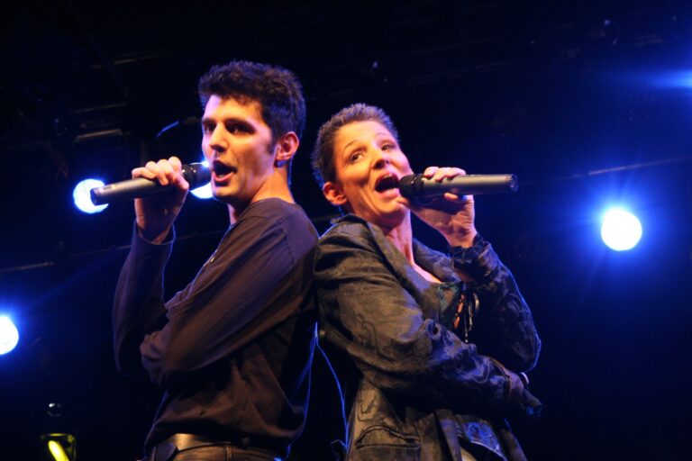 Roger Stein und Sandra Kreisler singen Rücken an Rücken auf der Bühne des Posthof Linz