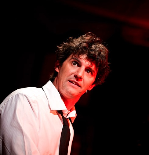 Roger Stein in weißem Hemd und Krawatte auf der Bühne