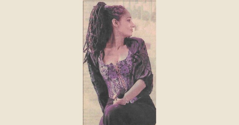 Sandra Kreisler mit langen Dreadlocks im violetten Spitzenoberteil, sitzend mit Mikrofon