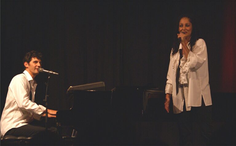 Roger Stein singt am Flügel, rechts steht Sandra Kreisler mit Mikrofon im weißen Rüschenhemd
