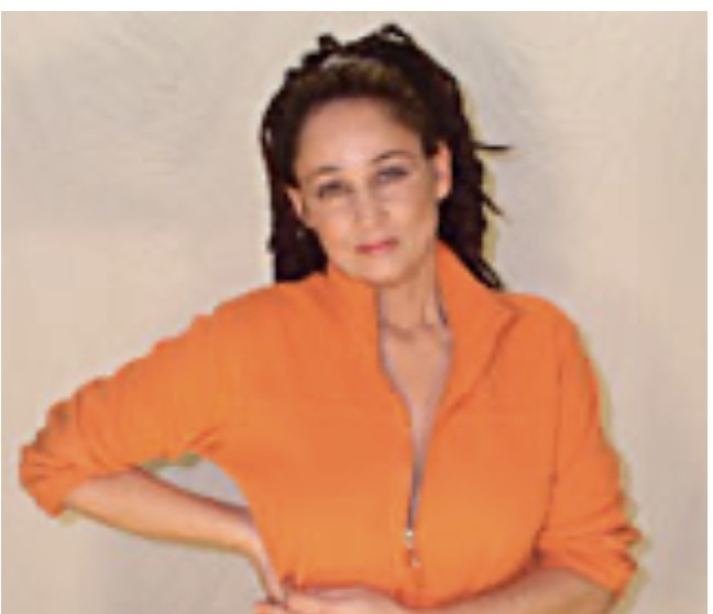 Porträt von Sandra Kreisler in oranger Jacke, die Hand in die Hüfte gestützt
