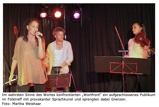 Sandra Kreisler singt am Mikrofon, dahinter Roger Stein, rechts Jolanta Stopka an der Geige, auf der Bühne des Folktreff Bonndorf