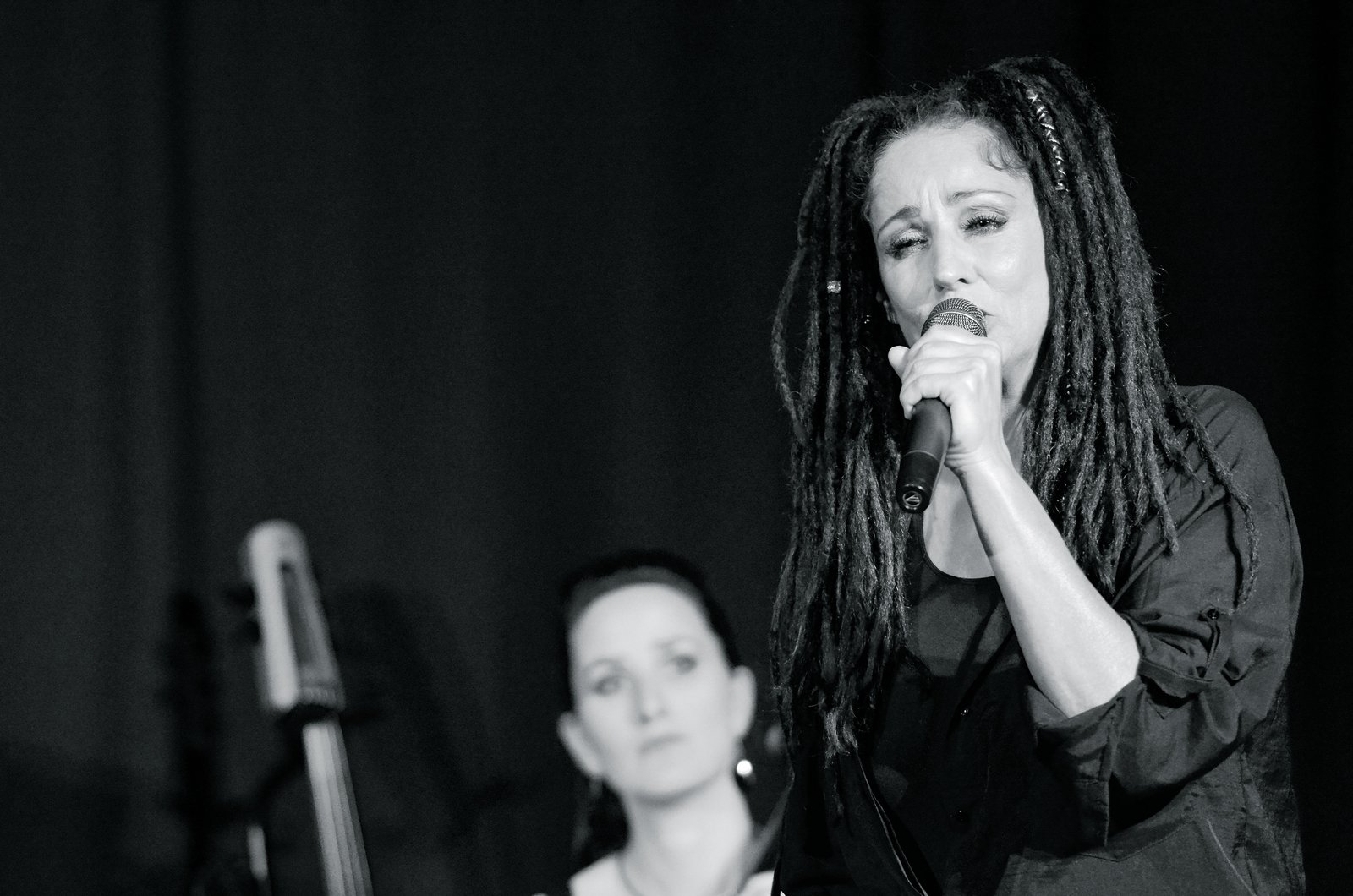 Sandra Kreisler singt ins Mikrofon, dahinter unscharf die Cellistin