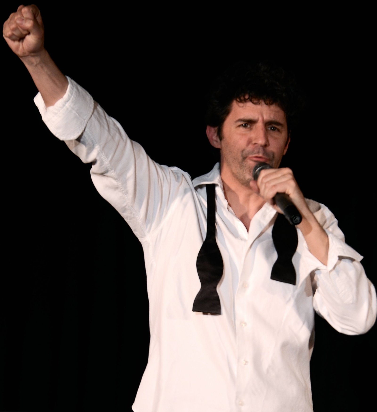 Roger Stein mit erhobener Faust und Mikrofon, offene Fliege