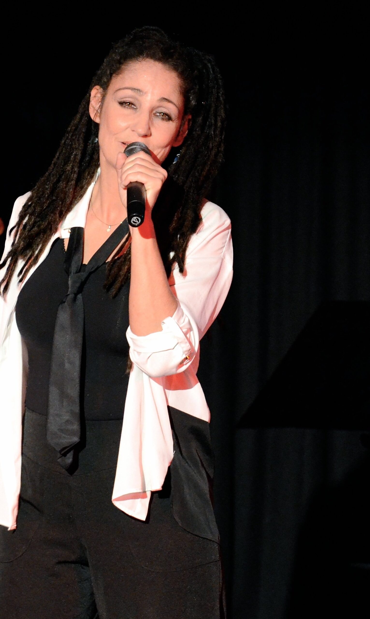 Sandra Kreisler singt ins Mikrofon, weiße Bluse und schwarze Krawatte