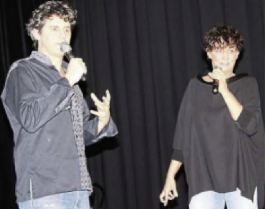 Roger Stein und Sandra Kreisler stehen mit Mikrofonen vor einem schwarzen Vorhang